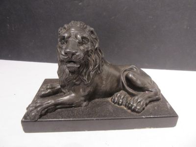 bronze statue of a lion on a base on a white table