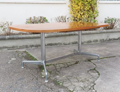 une table en bois avec un piètement en métal et une plante en arrière-plan