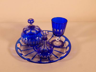 une assiette en verre bleu sur laquelle est posé un service à thé en verre bleu