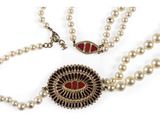 a close up of a necklace with pearls on a white background