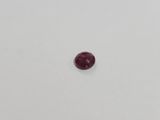 a single red ruby stone on a white surface