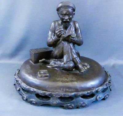 statue d'un garçon assis sur un plateau en argent, tenant un livre