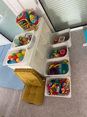 plusieurs bacs remplis de jouets dans un coin de la pièce