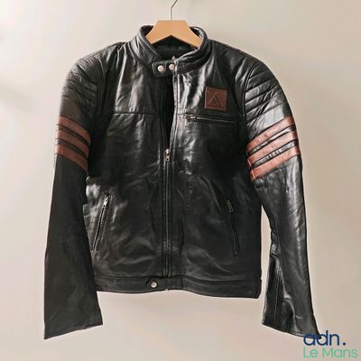 black leather jacket hanging on a hanger on a white wall