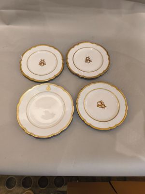 quatre assiettes blanches et dorées, ornées d'une bordure dorée, posées sur une table