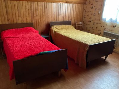 deux lits dans une chambre avec des lambris et une fenêtre