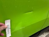 a hand that is holding a ruler near a green car
