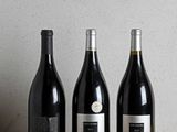 trois bouteilles de vin sont alignées sur une table en bois