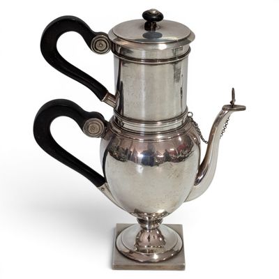a silver tea pot with a black handle on a stand