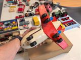 a person holding a toy airplane in front of a pile of toy cars