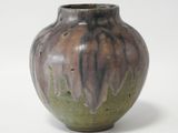 un vase marron et vert posé sur une surface blanche