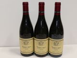 trois bouteilles de vin rouge sont posées sur une table blanche