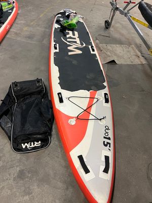 une planche de surf rouge et blanche posée par terre à côté d'autres bateaux