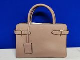un sac à main beige posé sur une table devant un mur bleu