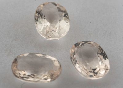 trois pierres de topaze blanche de tailles différentes posées sur une table