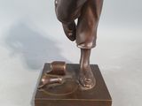 bronze statue of a man riding a bull on a wooden base