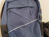 a blue backpack sitting on the floor next to a pair of jeans