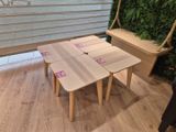 trois tables et un banc dans une pièce où une plante est accrochée au mur