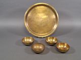 three brass bowls and a tray on a gray surface