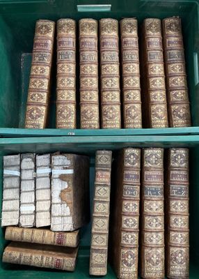 Plusieurs vieux livres sont empilés dans une poubelle verte posée sur une étagère