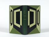 un livre ouvert, à la couverture verte, posé sur une table blanche