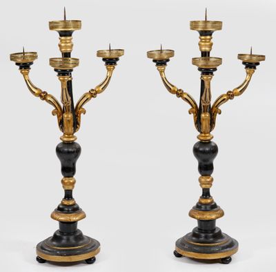 une paire de chandeliers noirs et dorés avec des bougies