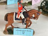 several figurines of men in uniforms riding on horses in a display case