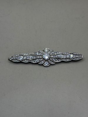 a close up of a diamond broochle on a gray surface