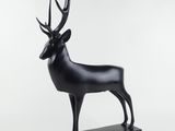 une sculpture noire représentant un cerf, posée sur un socle en marbre