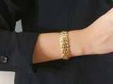 une femme vêtue d'un tailleur noir et portant un bracelet en or