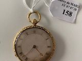 a gold pocket watch hanging on a white wall