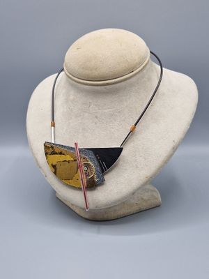 leather necklace with gold and black triangle pendant on a mannequin head