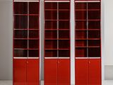 trois bibliothèques rouges dans une pièce aux murs blancs