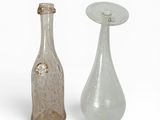 deux bouteilles en verre posées l'une à côté de l'autre sur une surface blanche