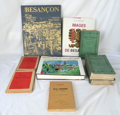 Plusieurs livres sont posés sur un lit recouvert d'un drap blanc.