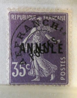 un vieux timbre violet sur lequel figure une femme tenant un panier de fleurs