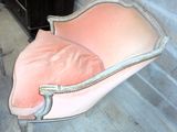 une chaise rose posée devant un mur de briques