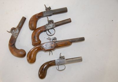 four old guns are lined up on a white surface