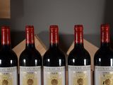 four bottles of red wine are lined up on a table
