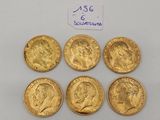 six gold sovereigns of different sizes and shapes on a white surface