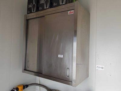 une armoire murale en acier inoxydable, placée dans un coin de la pièce