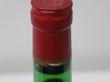 a close up of a bottle of wine with a red cap