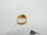 une bague en or posée sur une table blanche, avec un fil blanc