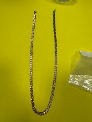 un collier et une paire de ciseaux posés sur une table jaune