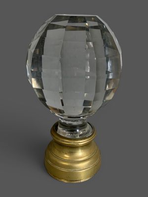 une boule de verre avec un socle doré sur fond gris