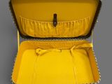 an open suitcase with a yellow lining inside of it on a gray surface