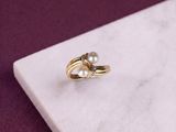 pearl and diamond ring on a marble slab on a purple background