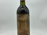 une vieille bouteille de vin posée sur une surface blanche