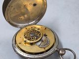 a silver pocket watch with a gold dial on it