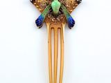 a gold hair comb with a green and blue bird on it